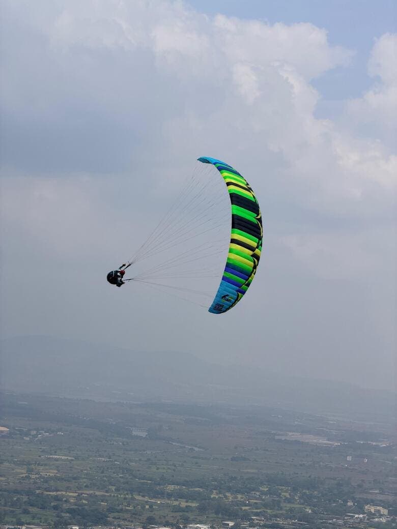 Tandem paraglider over the green ridges of Kamshet